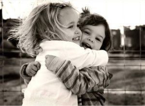 Black and white image of young children hugging adorably